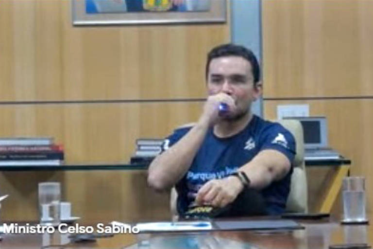 O ministro do Turismo, Celso Sabino, fuma um cigarro eletrônico em seu gabinete durante entrevista coletiva