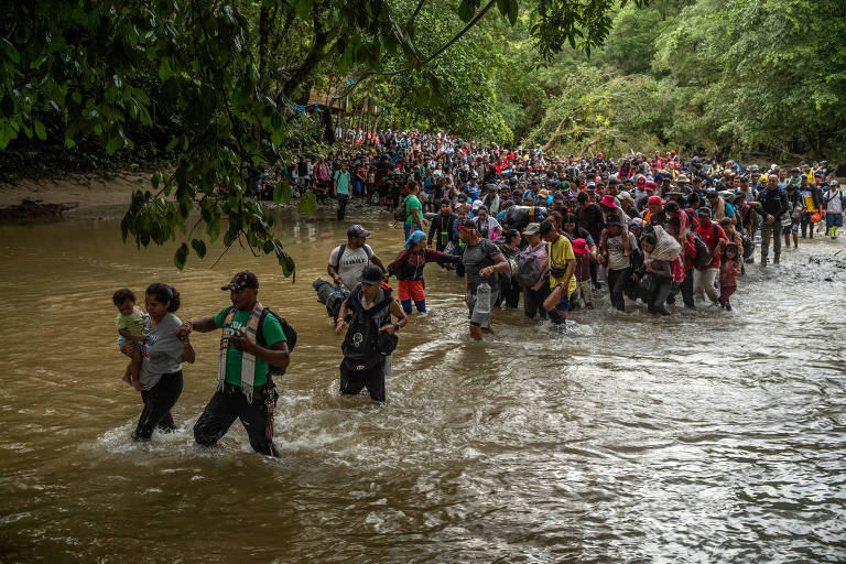 Migrants walk into a river in the Darién Gap in Colombia