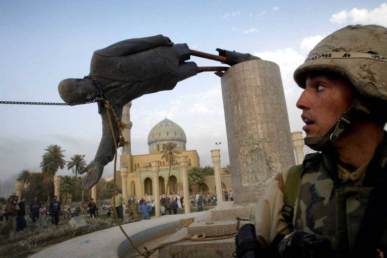 Militar americano vê estátua de Saddam Hussein ser derrubada em praça no centro de Bagdá, em abril de 2003