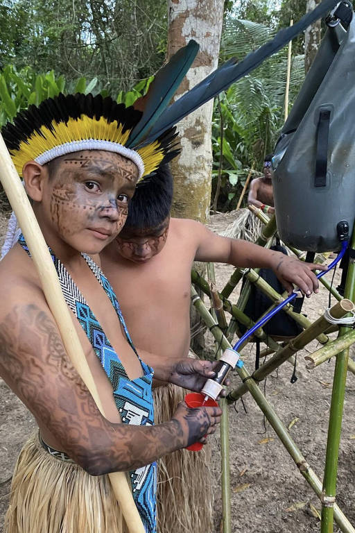 Dois meninos indígenas interagem com filtro de água