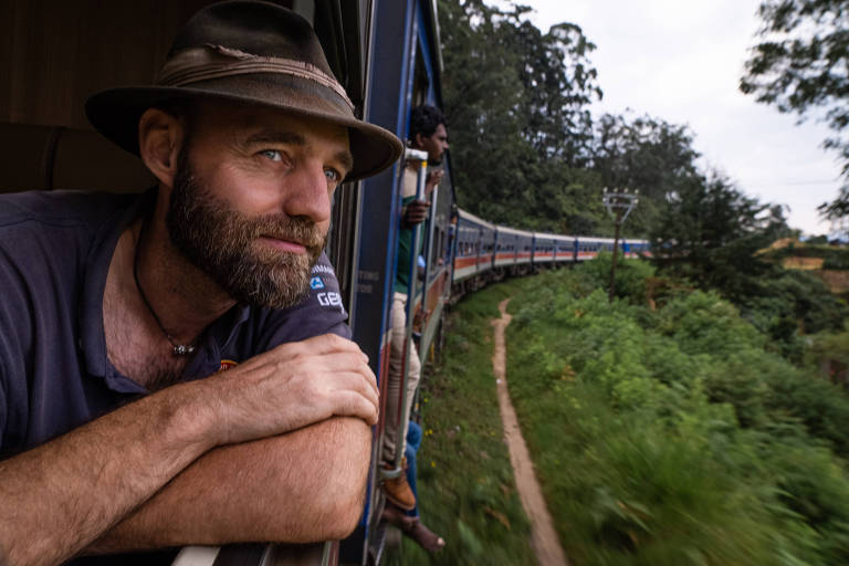 homem branco de barba e chapéu na janela de um trem