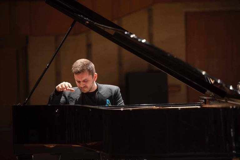 Em foto colorida, o pianista Kamil Pacholec aparece tocando