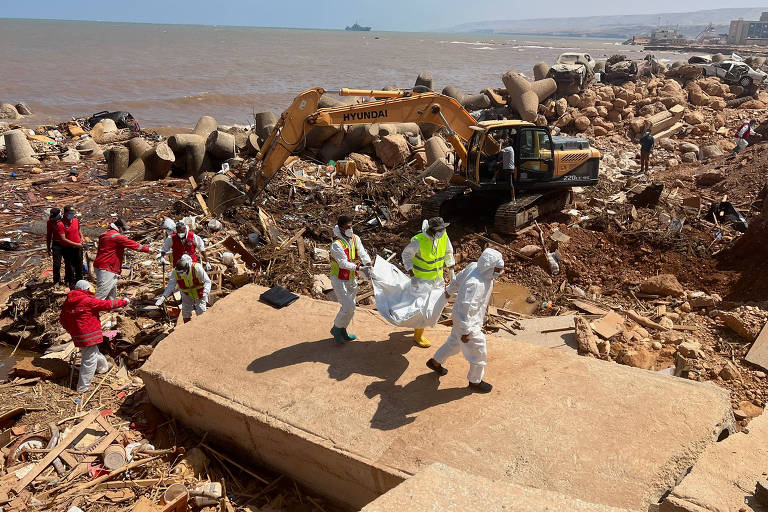 Equipes de resgate carregam corpo de vítima das enchentes encontrado em praia de Derna, na Líbia