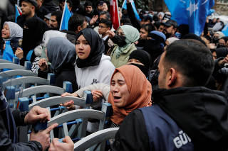 Ethnic Uighur demonstrators scuffle with riot police as they try to continue a sit-in protest against China