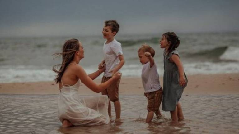 Mãe e três filhos pequenos numa praia