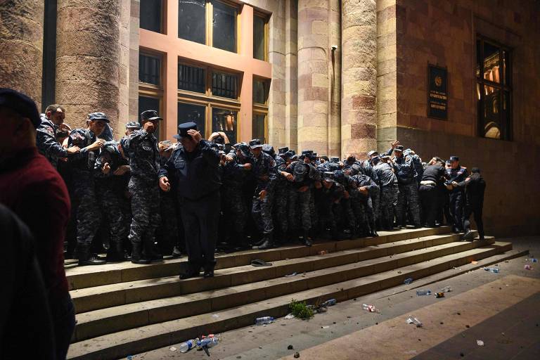 Policiais armênios guardam a entrada do prédio do governo durante confrontos com manifestantes que pedem a renúncia do primeiro-ministro armênio, Nikol Pashinyan, no centro de Ierevan