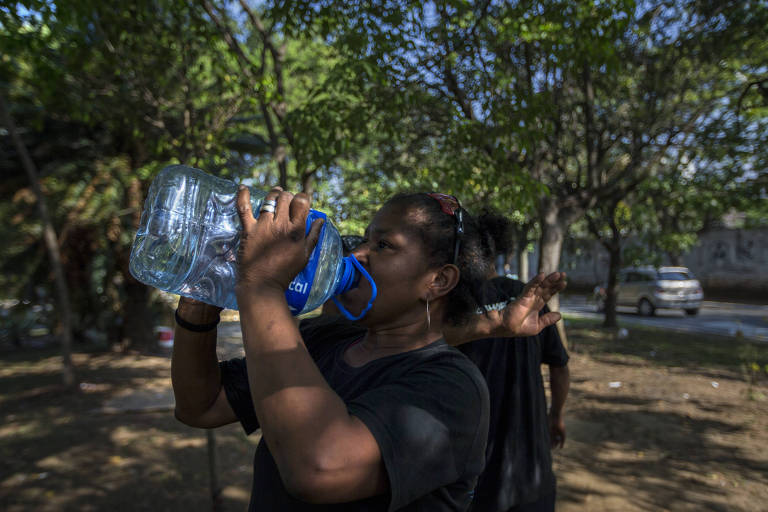 Morador de rua bebe água em uma garrafa plástica
