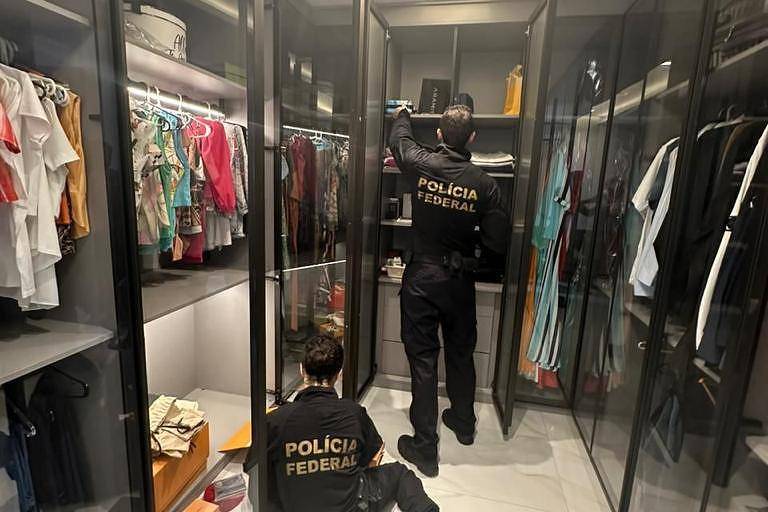 Dois policiais verificando documentos e objetos em um amplo closet