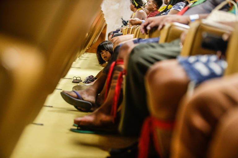 Detalhe das pernas de indígenas, pintadas e enfeitadas com fitas, sentados no plenário do STF