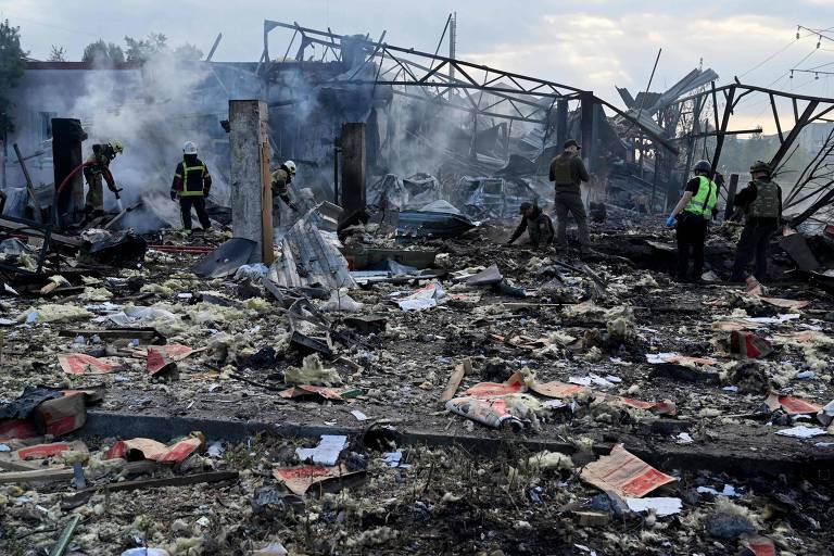 Bombeiros e especialistas em explosivos trabalham após ataque com míssil em Kiev nesta quinta (21)