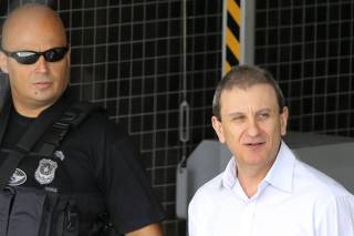 Businessman and money changer Alberto Youssef, is escorted by a federal policeman before a hearing at the federal court in Curitiba