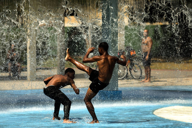 Imagem mostra jovens e crianças se refrescando do calor nas águas do Parque de Madureira, no Rio de Janeiro