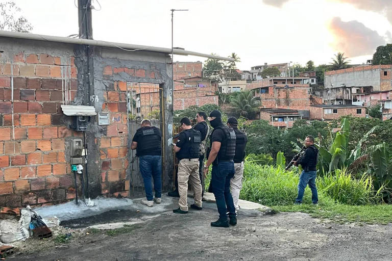 Policiais armados em frente ao portão de uma residência