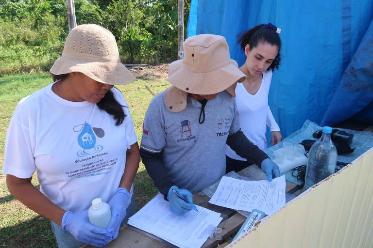 Imagem mostra três pesquisadoras analisando resultados de amostras de água