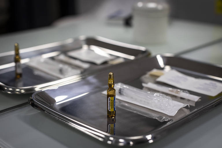 ampola com medicamento está em pé em bandeja prata, além de seringa utilizada para aplicação