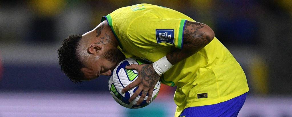 Neymar segura a bola com as duas mãos e a beija na partida do Brasil contra a Bolívia, em Belém, pelas Eliminatórias da Copa do Mundo de 2026; ele usa camisa amarela e calção azul