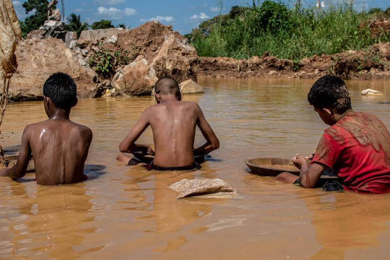 Três crianças sentadas na lama