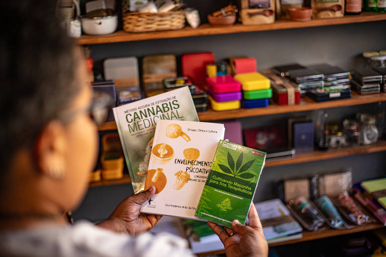 Maielle Almeida, 28, vendedora da tabacaria 'Isso é um cachimbo?', segurando livros vendidos na loja, em Salvador, BA