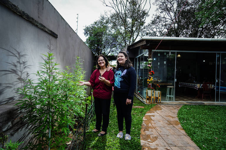 Liane Pereira e sua filha, Caroline, ao lado de pés de Cannabis na casa da família em Canoas (RS)
