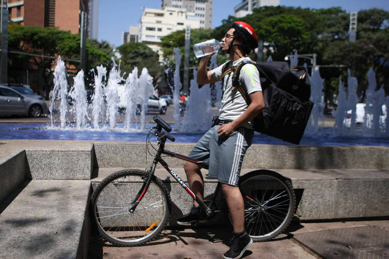 Homem interrompe pedalada e toma água em cima de bicicleta