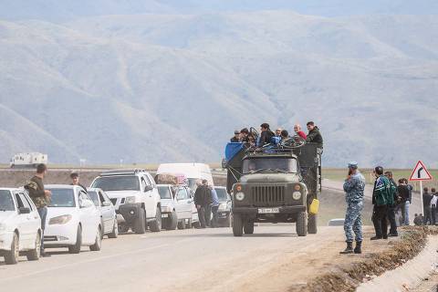 Refugees sit in a truck driving down a road after crossing the border, near the town of Kornidzor, on September 26, 2023. Hundreds of vehicles were heading to Armenia from Nagorno-Karabakh on September 26, 2023,  following Azerbaijan's lightning offensive against the separatist enclave, an AFP team at the scene said. (Photo by Alain JOCARD / AFP)