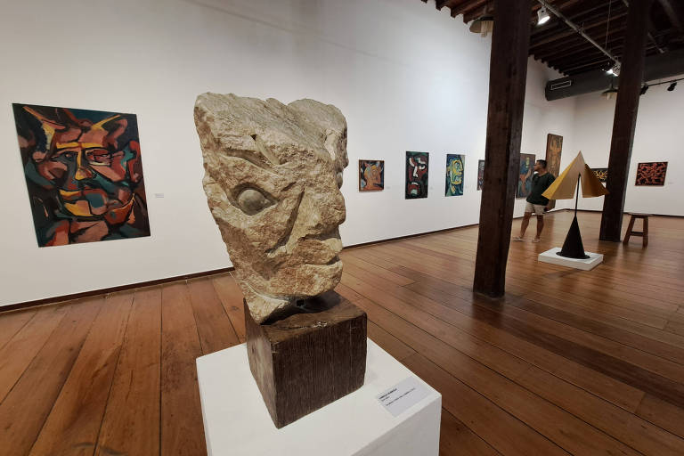 escultura de pedra com quadros ao fundo em ala do museu de arte moderna da bahia