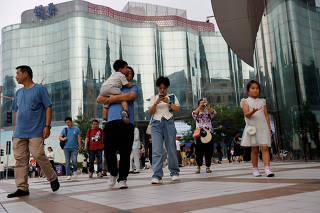 FILE PHOTO: People walk at a shopping area in Beijing