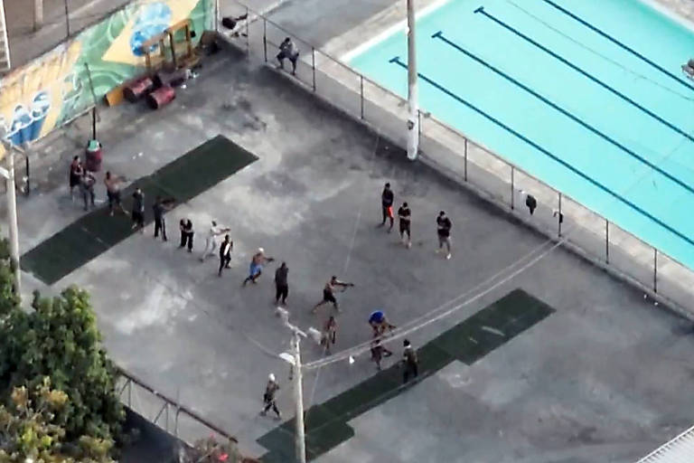 Imagem aérea mostra dezenas de homens armados, com fuzil, em uma espécie de treinamento de guerrilha em uma área de lazer com quadra e piscina no Complexo da Maré.