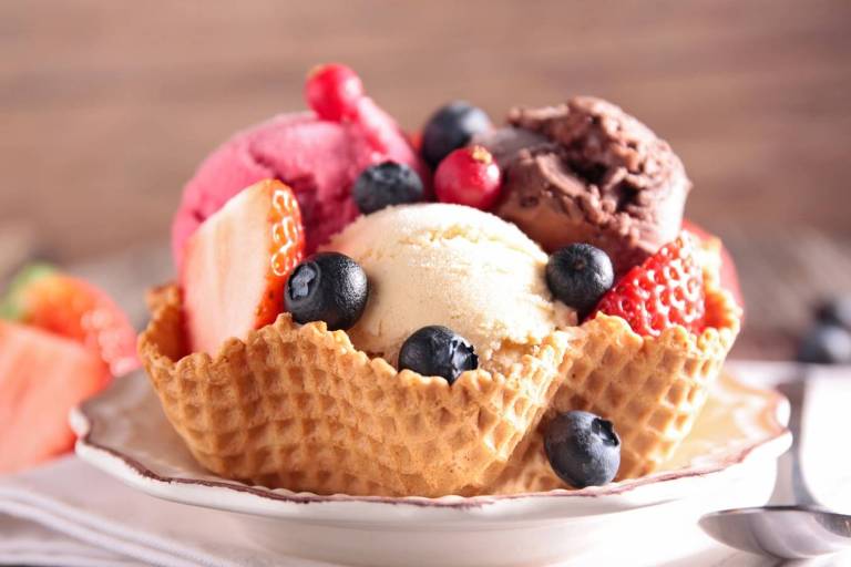 Imagem mostra sorvetes de creme e chocolate em uma casca comestível e frutas