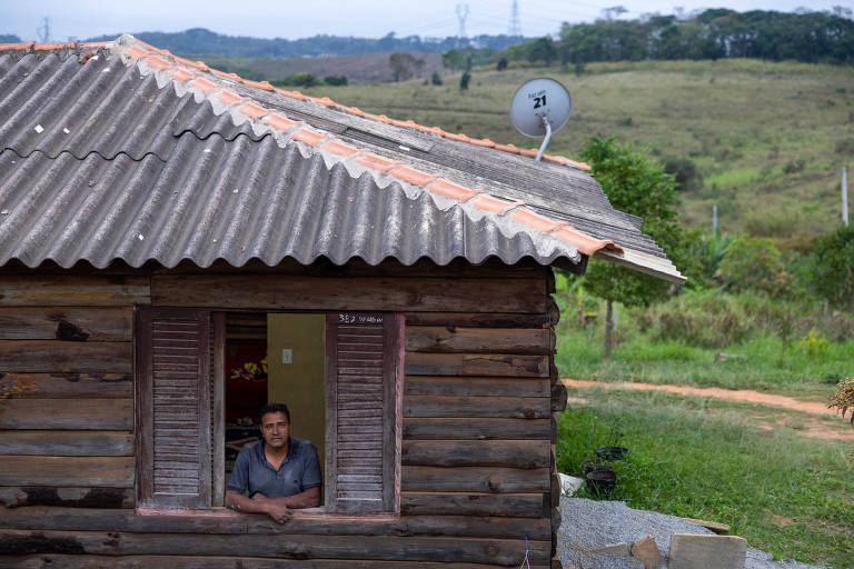 Imagem Isaque na janela de sua casa, que tem paredes de madeira  