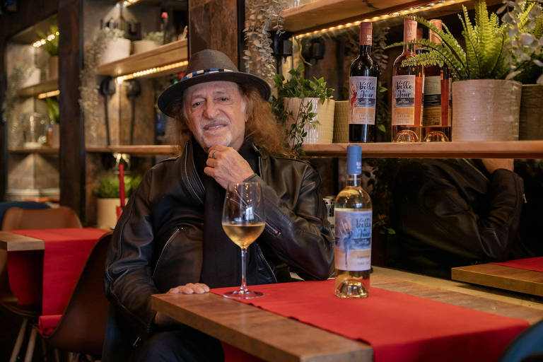 Cantor Alceu Valença posa ao lado de uma garrafa e taça de vinho