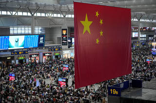 People wait to board trains at the Shanghai Hongqiao railway station ahead of the National Day holiday, in Shanghai