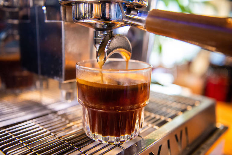 Café sendo extraído de uma máquina em um copo de vidro