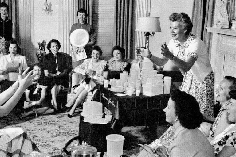 Brownie Wise joga um recipiente plástico cheio de água em uma festa da Tupperware na década de 1950