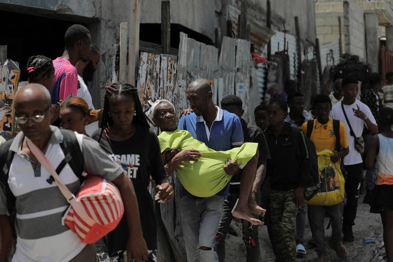 Moradores carregam pertences pessoais ao terem de deixar suas casas na região de Carrefour Feuilless, na capital Porto Príncipe, devido à violência armada