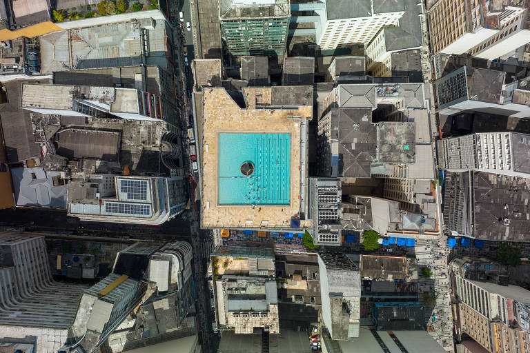 Imagem aérea mostra piscina no topo do prédio. A cor azul faz a laje se destacar