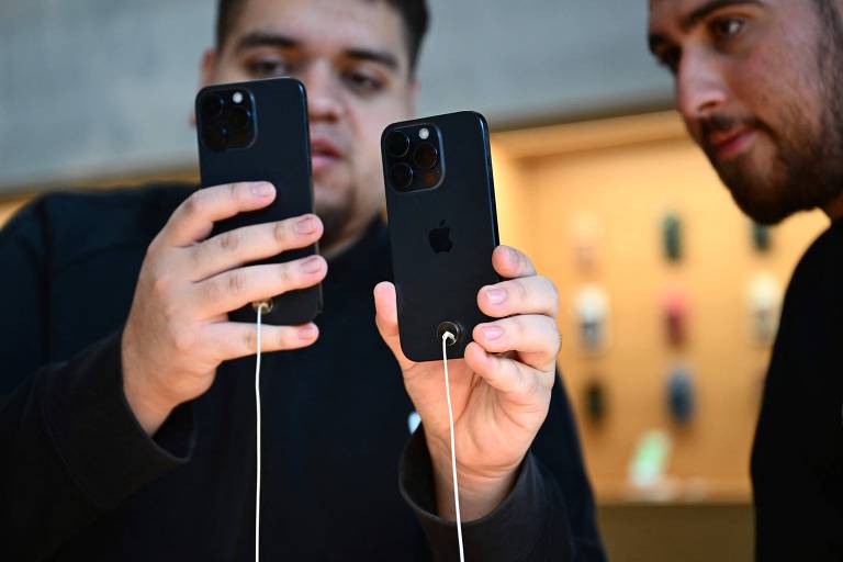 Funcionário de loja da Apple exibe o iPhone 15 Pro para um cliente em loja nos Estados Unidos