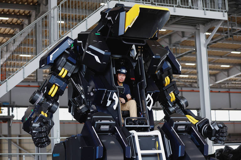 Homem sentado dentro de robô mostra como é feito o controle do traje, que vira veículo