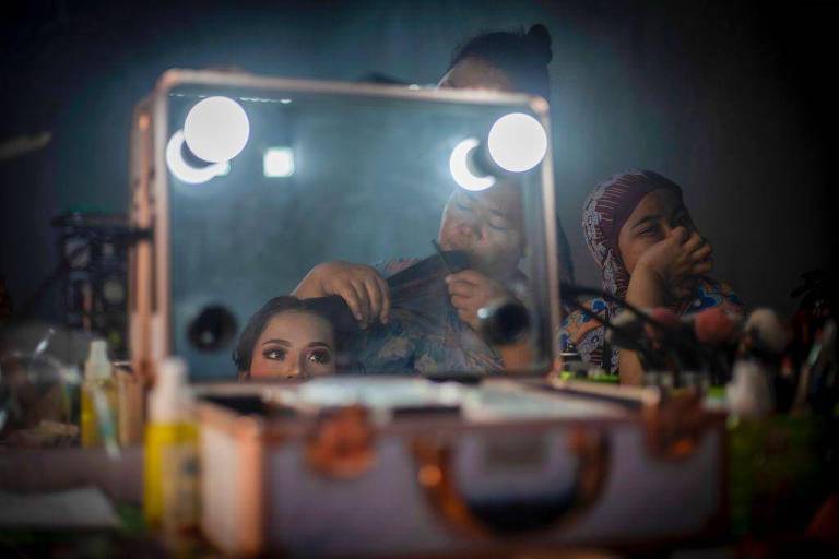 Jovens fazem maquiagem diante de espelho