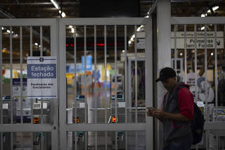 Homem aguarda diante do portão fechado da estação Tatuapé, da linha 3-vermelha