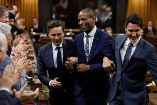 Newly elected Speaker Greg Fergus pretends to resist while being walked through the House of Commons by Canada's Prime Minister Justin Trudeau and Conservative Party of Canada leader Pierre Poilievre on Parliament Hill in Ottawa