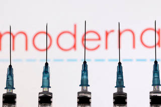 FILE PHOTO: Syringes with needles are seen in front of a displayed Moderna logo in this illustration taken