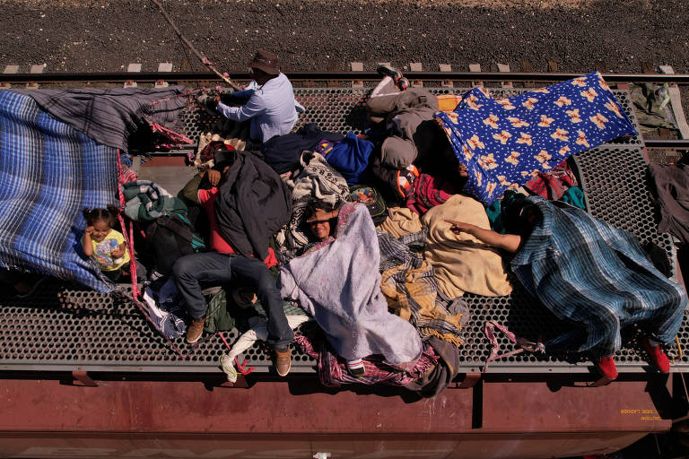 Grupo de migrantes se aconchega como pode no teto de um trem de carga em direção à fronteira mexicana com os Estados Unidos