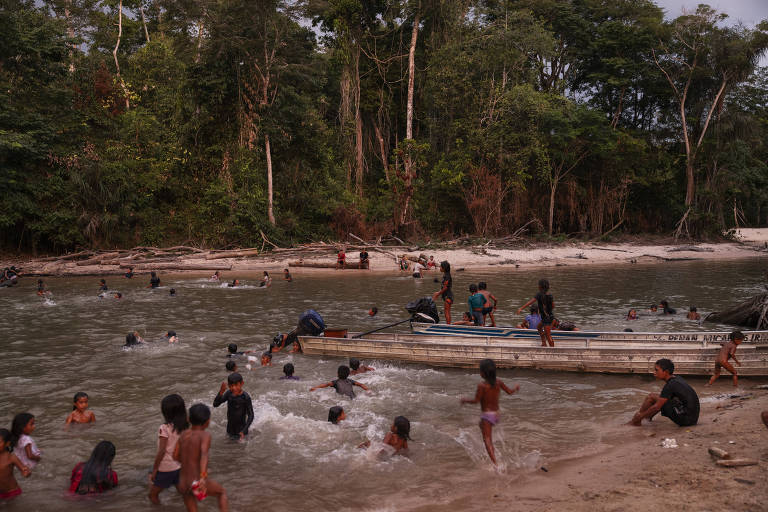 Crianças tomam banho em rio