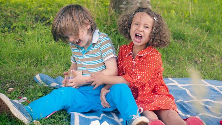 Um menino e uma menina brincando num gramado de parque