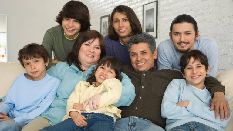 Família numerosa sentada no sofá, com os pais e seis filhos