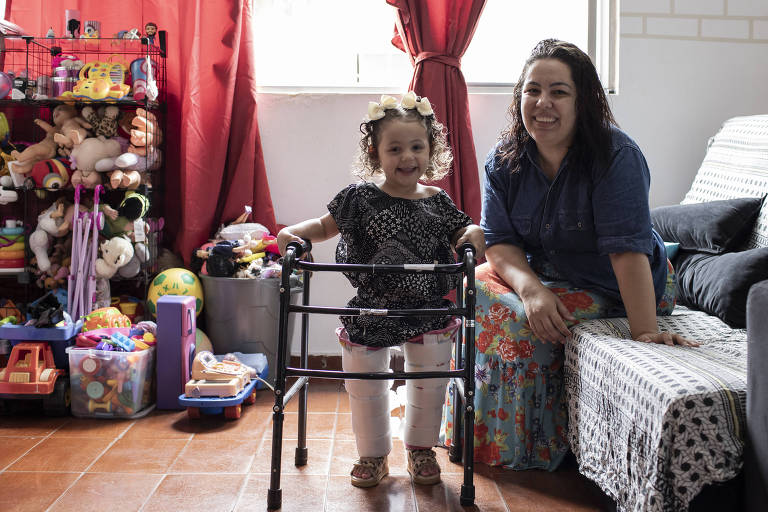 Maria Sofia, 3, que tem AME tipo 2 e tomou o remédio Zolgensma, ao lado de sua mãe, Renata Santana
