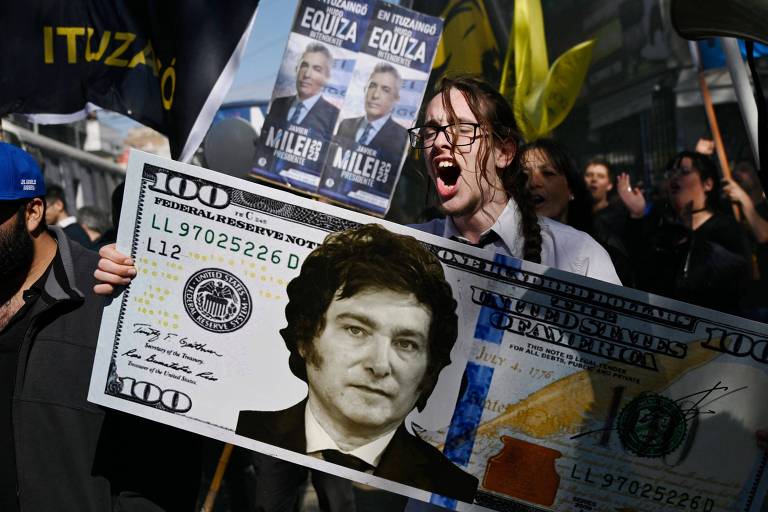 Apoiador de Javier Milei segura nota de US$ 100 com o rosto do candidato argentino à Presidência