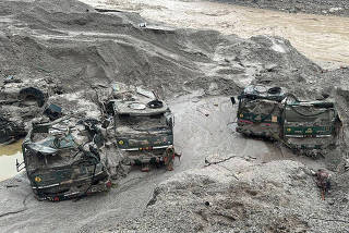 Trucks buried in mud are seen in an area affected by flood in Sikkim