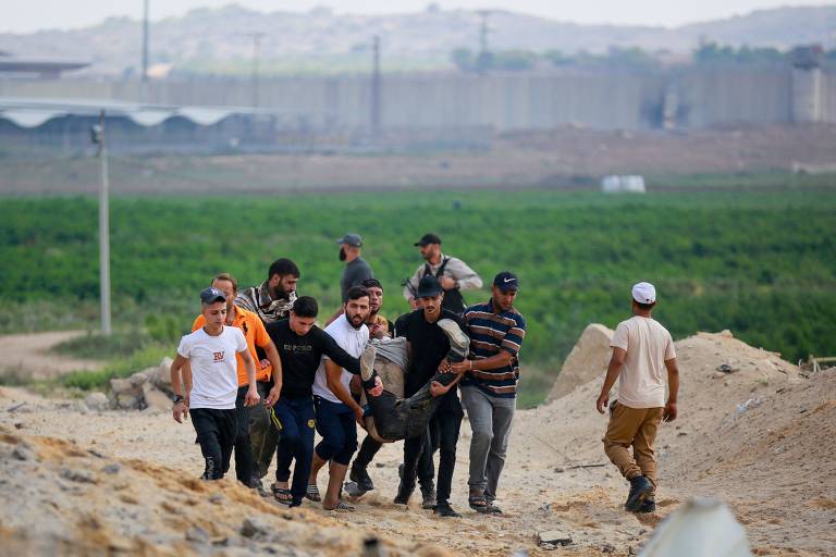 Palestinos carregam jovem ferido após ataques aéreos de Israel em Erez, na fronteira entre Israel e a Faixa de Gaza